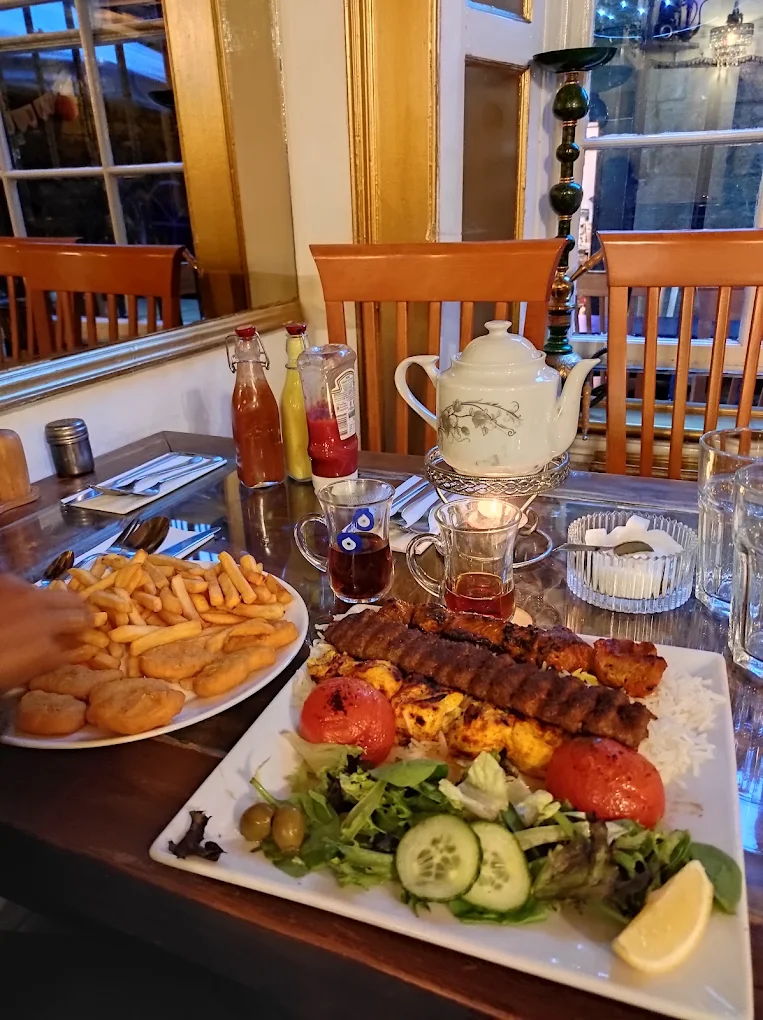 Persian dining setup featuring grilled kebabs, side salad, and hot tea in Edinburgh.