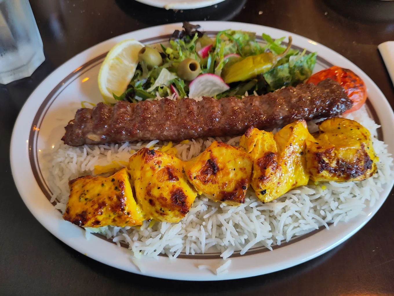 Chicken and minced meat kebabs over saffron rice with fresh salad at Toranj restaurant in Edinburgh.